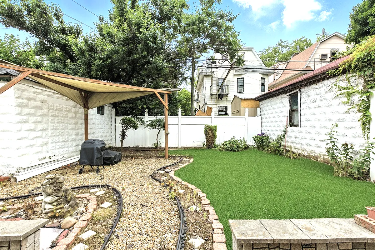rear yard with a pebble pathway to a covered area with a bbq