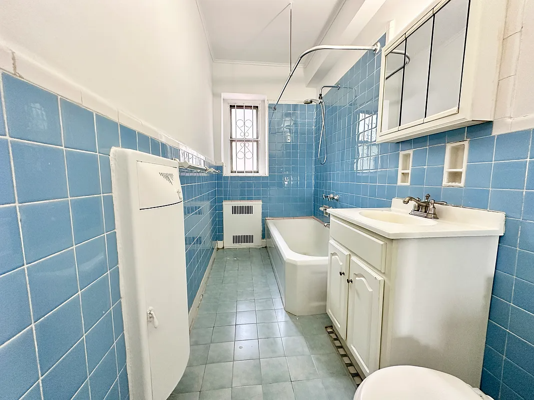 bathroom with white fixtures, a laundry hamper and blue wall tile