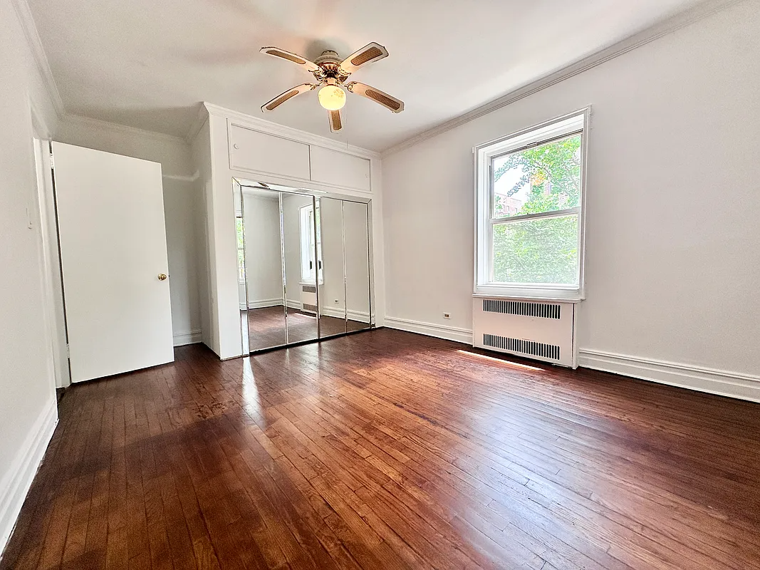 bedroom with wood floor, ceiling fan, mirrored closet doors