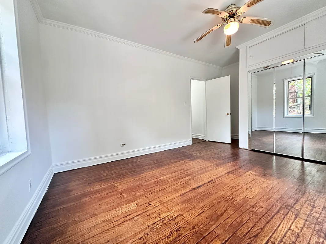bedroom with wood floor, ceiling fan, mirrored closet doors