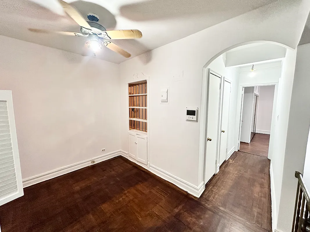 foyer with a niche with shelves and an arched doorway to a hall with closets