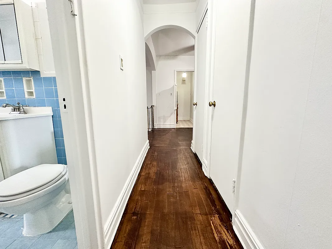 hallway from bedroom with a glimpse of a bathroom with blue tile