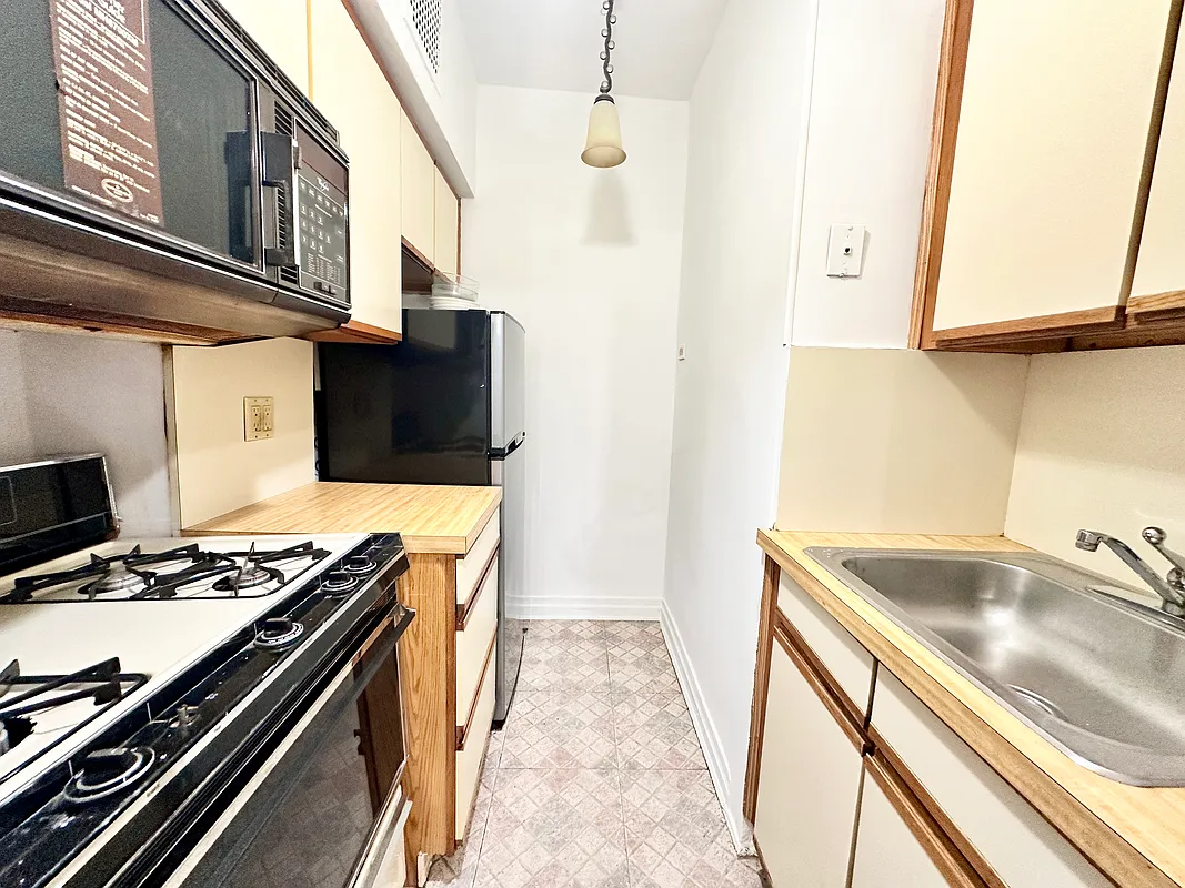 kitchen with laminate cabinets with wood trim, faux wood laminate counter and black appliances