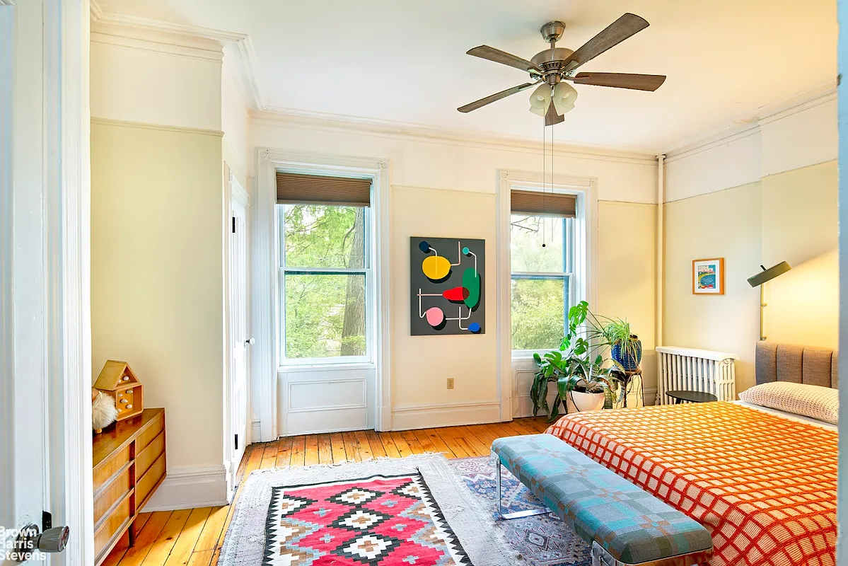 a bedroom with wood floor, a ceiling fan, and picture rails