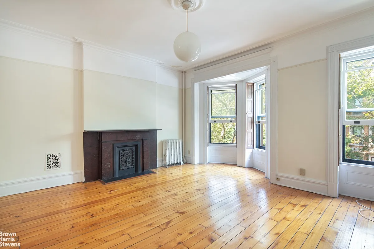 a bedroom with a mantel, wood floor, picture rails