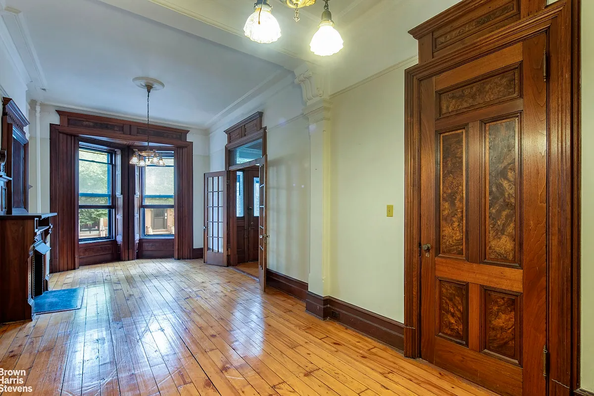 parlor with wood floor, moldings, unpainted woodwork, mantel