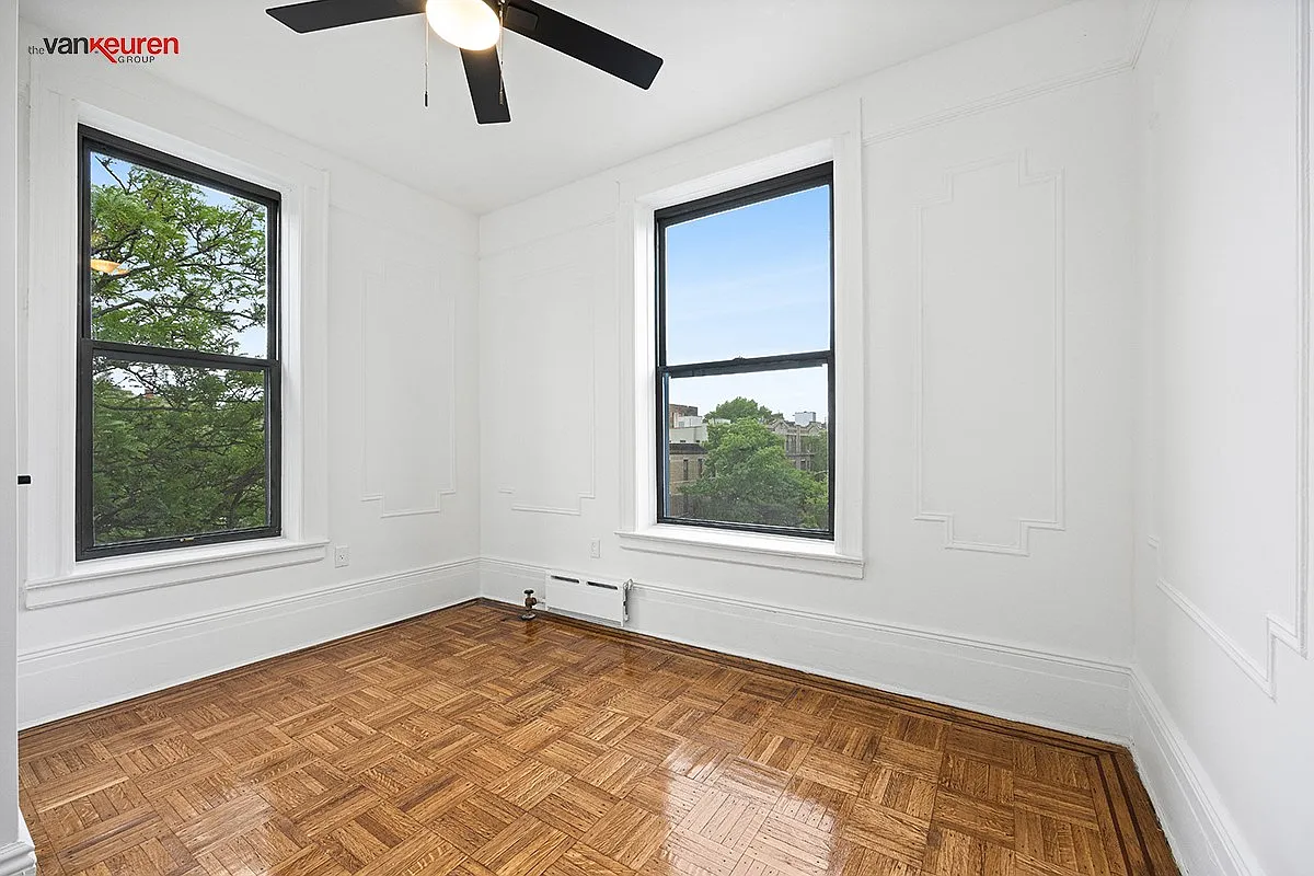 a bedroom with a wood floor, two exposures and a ceiling fan