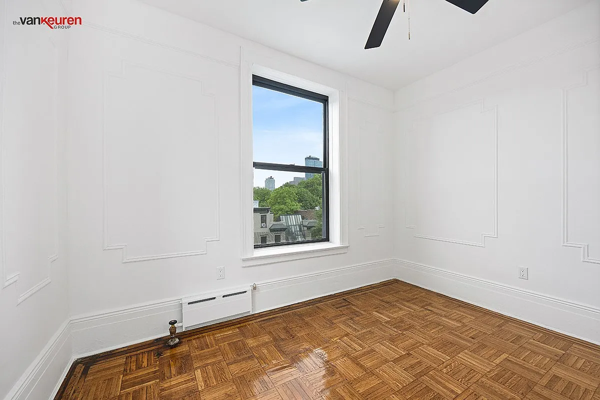 a bedroom with a wood floor, wall moldings and a ceiling fan