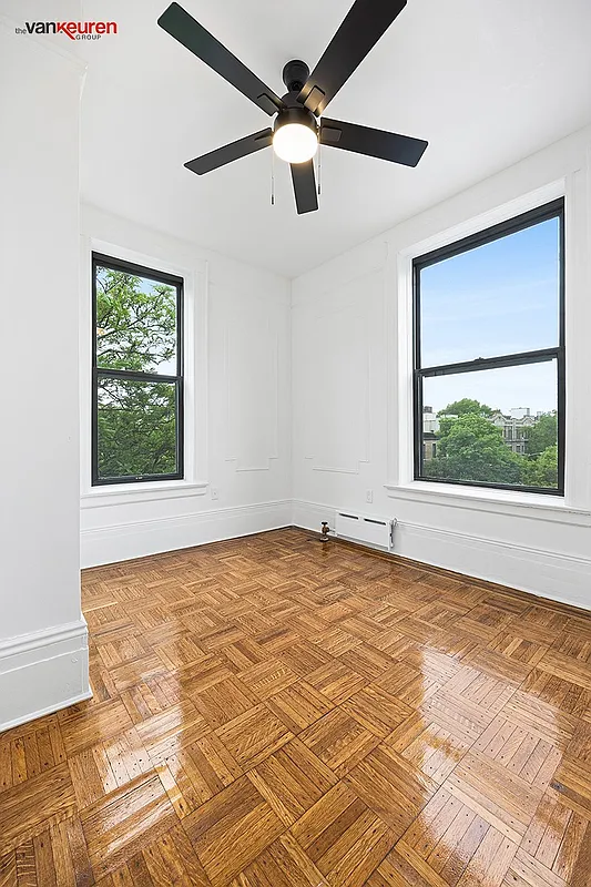 a bedroom with a wood floor, two exposures and a ceiling fan