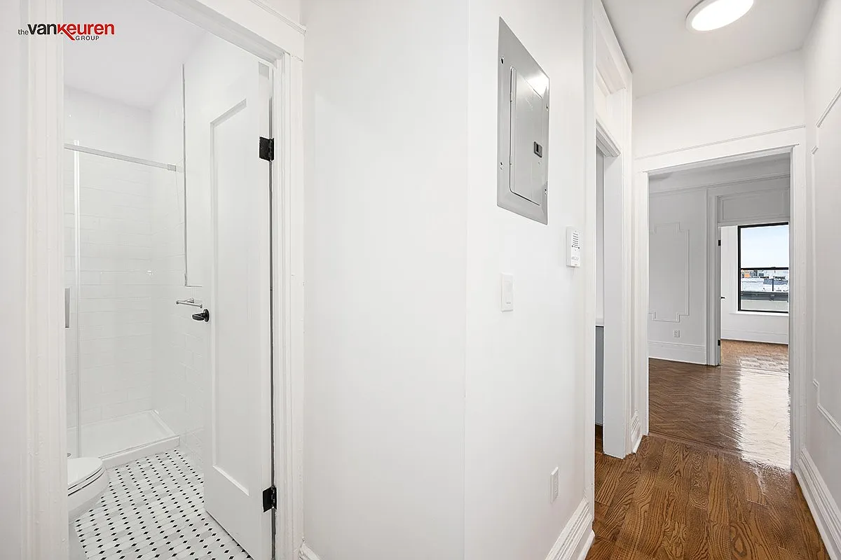 a hallway with white walls and a view into the bathroom