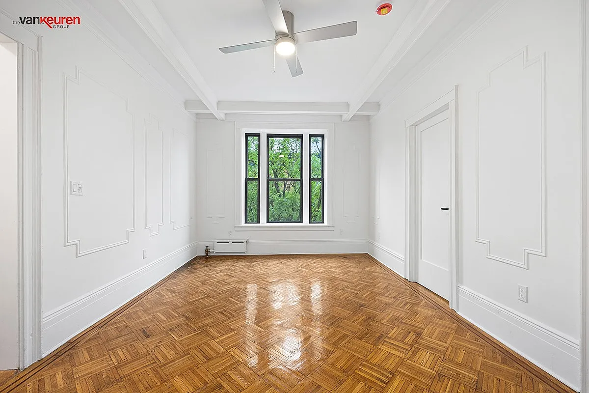 a living room with wall moldings, a wood floor and a ceiling fan