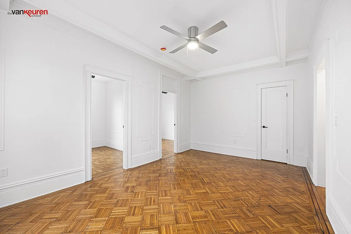 a living room with a wood floor, a ceiling fan and doors to the two bedrooms