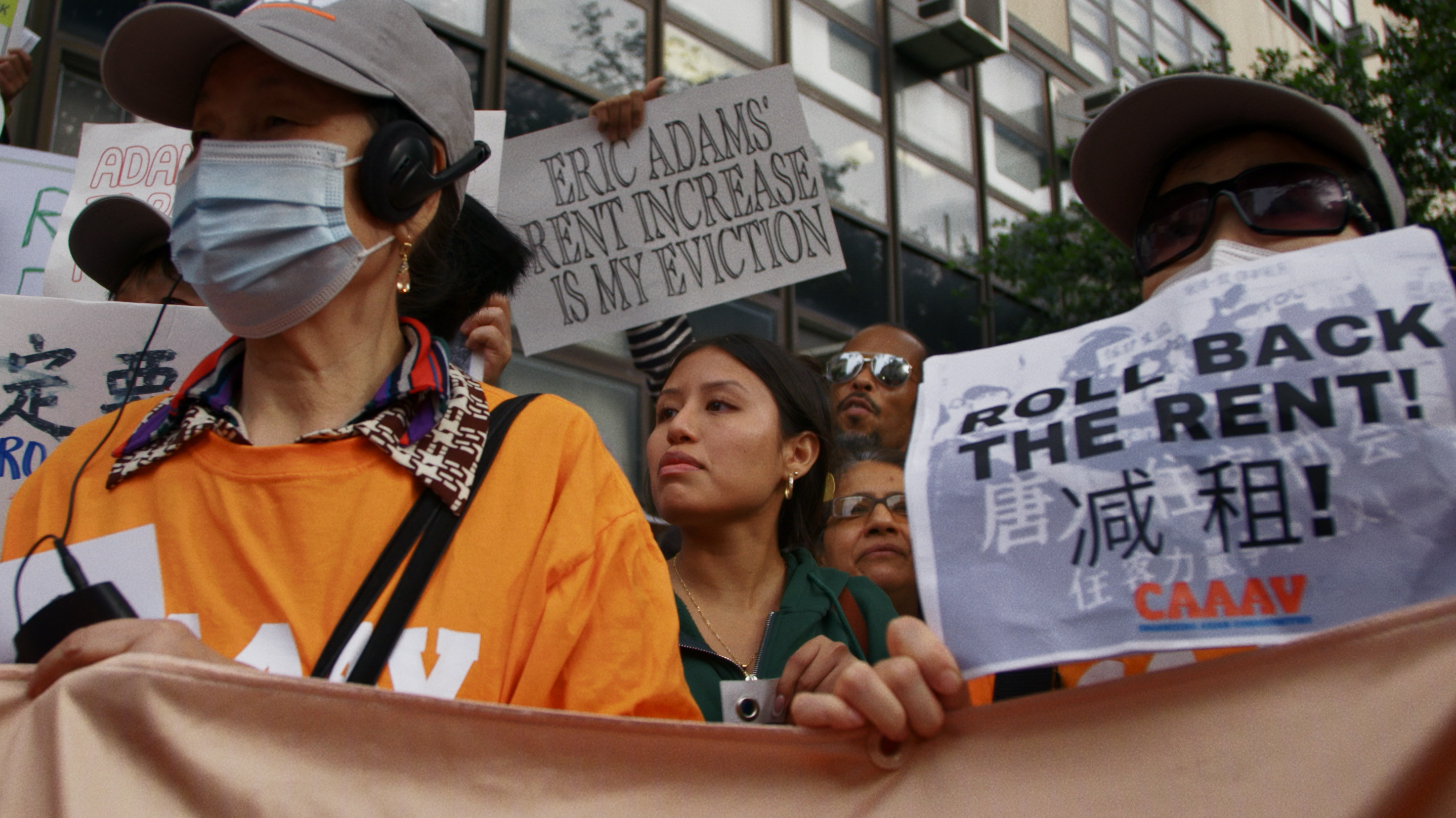 people holding signs about rent and evictions at a rally