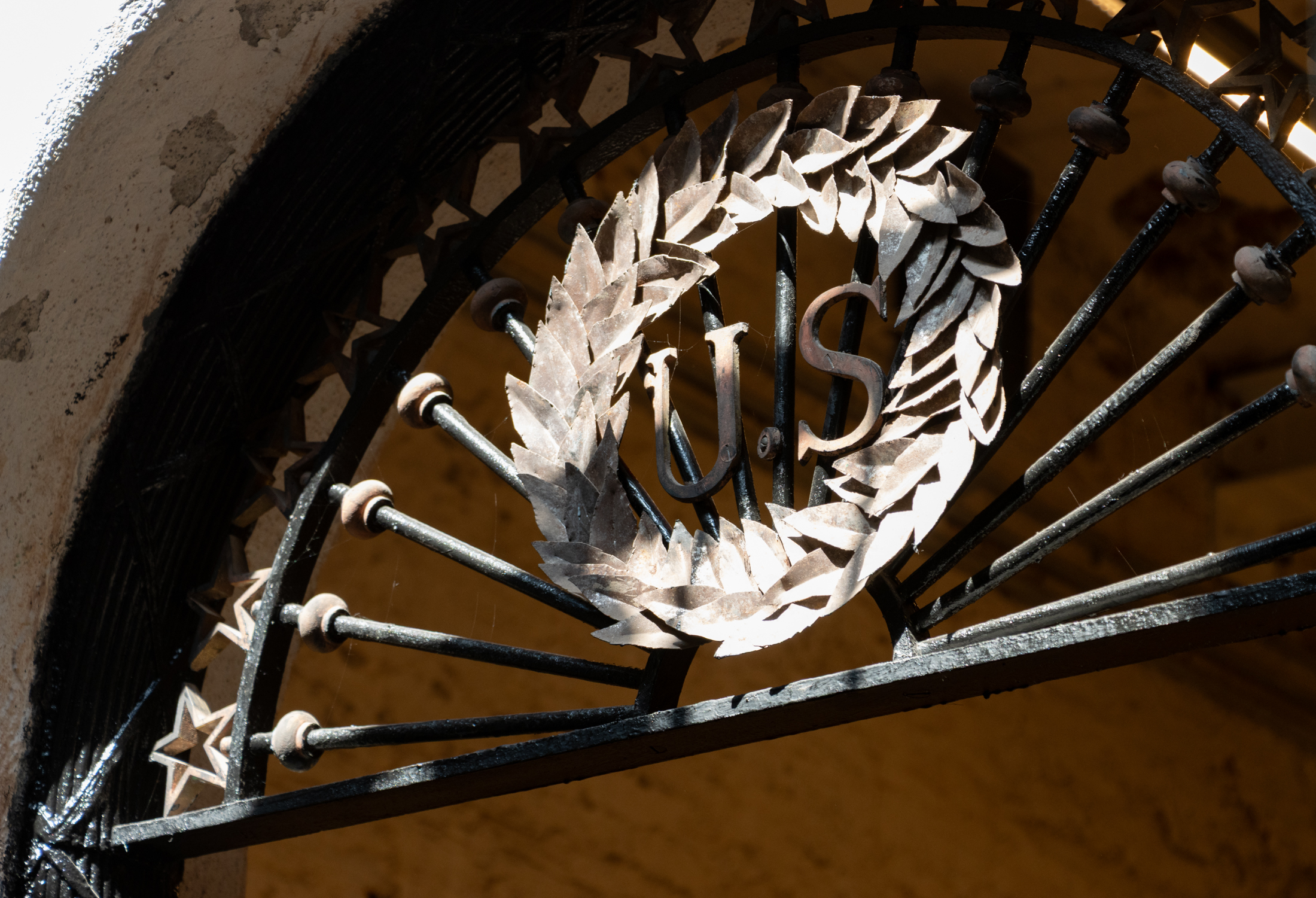 decorative ironwork, including a wreath with a US in it, above a doorway