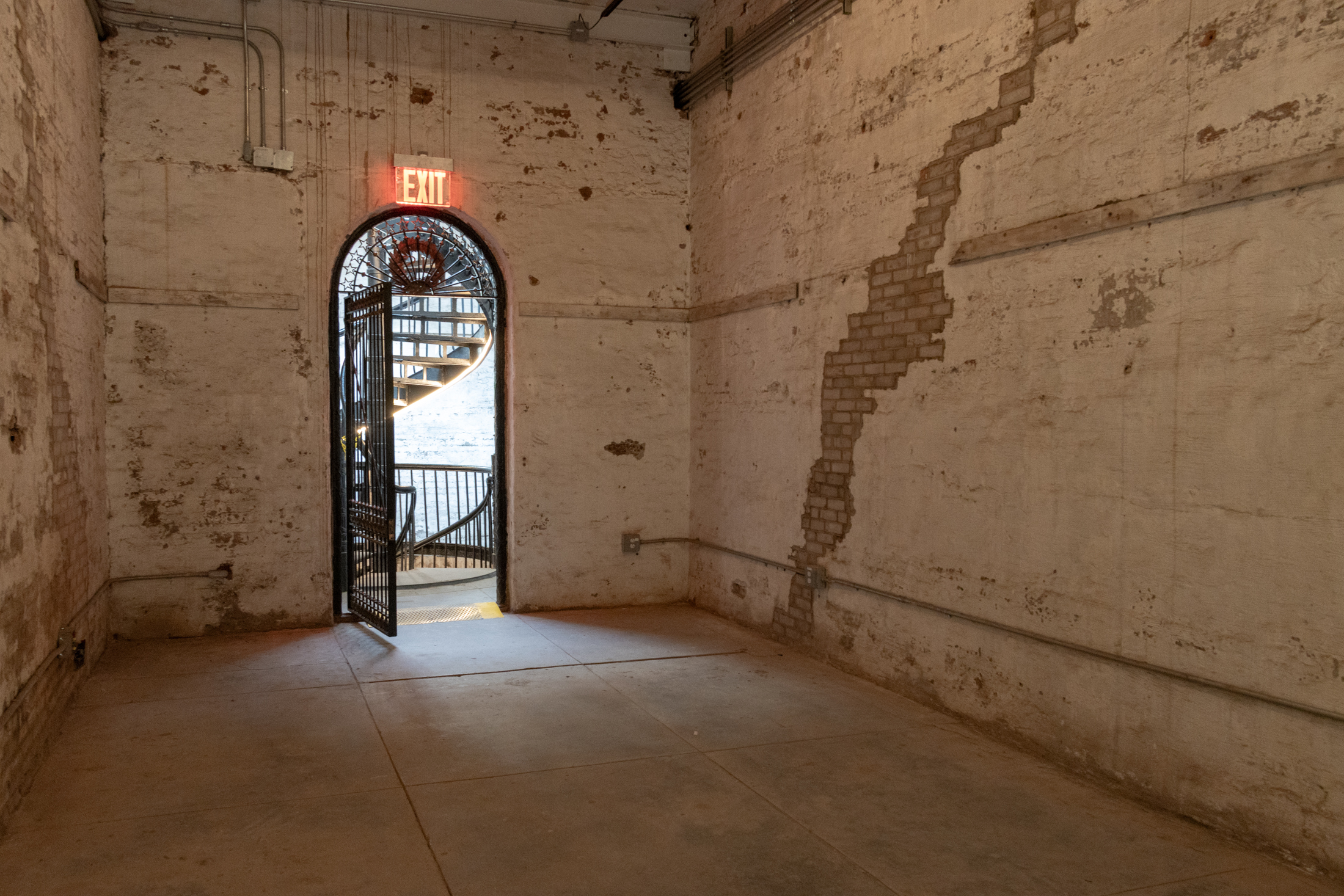 room with plaster covered brick and view through to a staircase