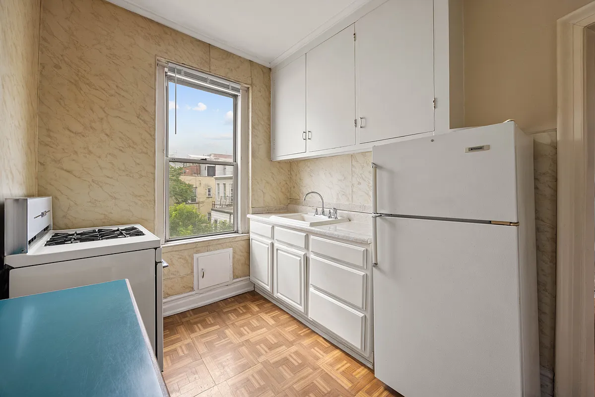 windowed kitchen with parquet tiles, white cabinets and appliances and beige wallpaper
