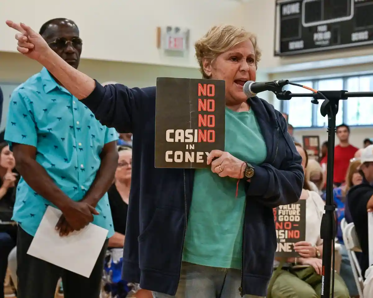 person holding a sign saying no casino standing at a microphone