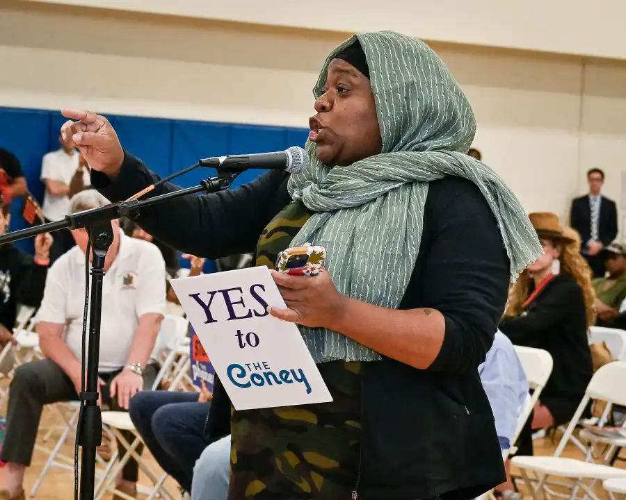 person at a microphone holding a sign supporting the casino