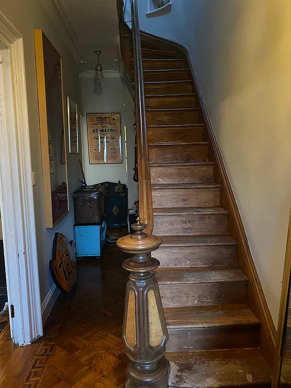 original newel post and curving stair with a glimpse of a coffin corner