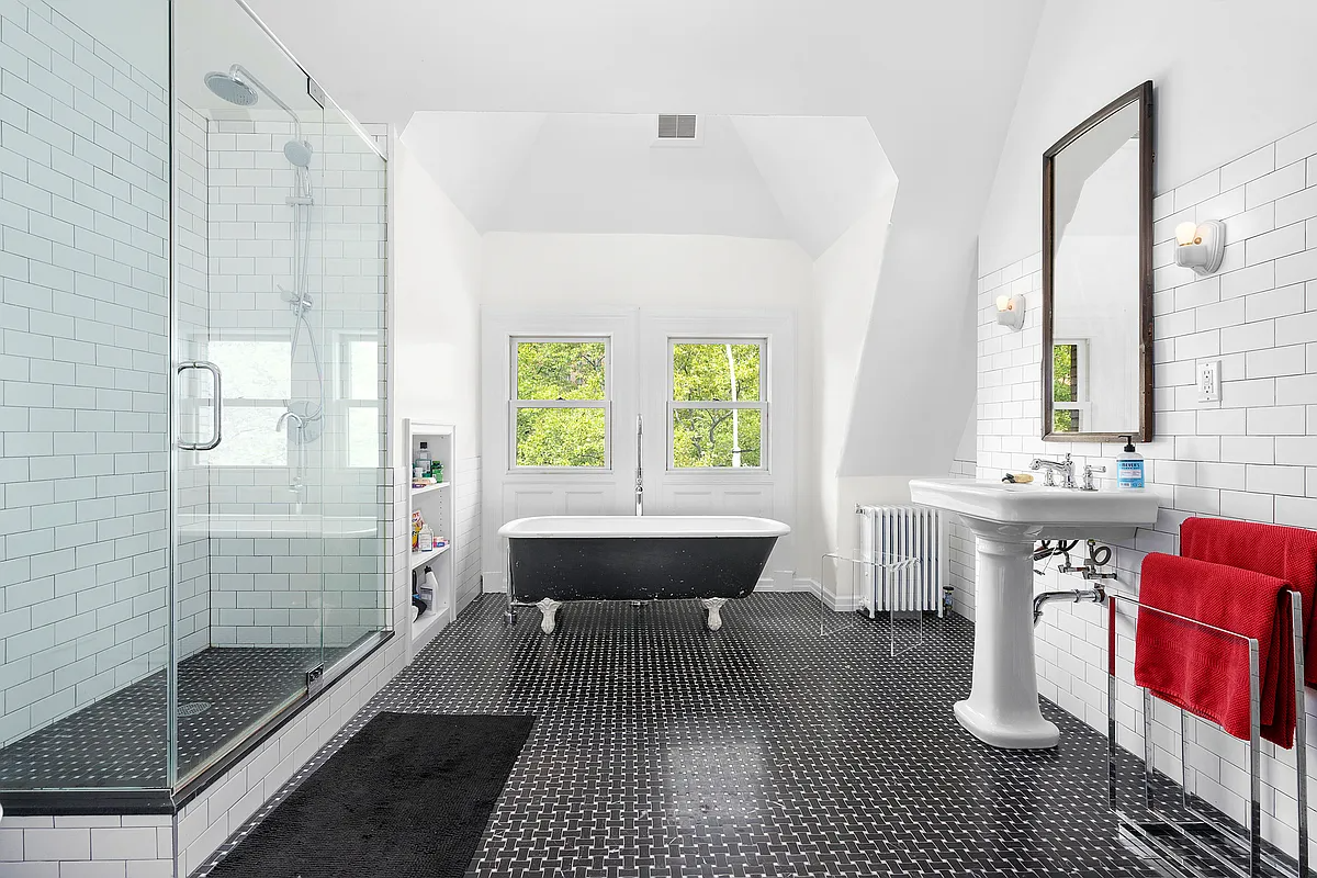 bathroom with black and white floor tile, a shower with glass doors, and a cast iron tub painted black