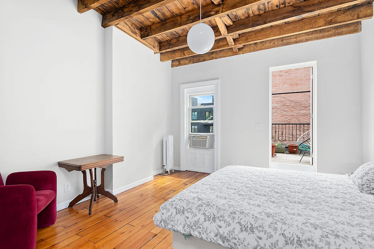 bedroom with exposed rafters and a door to a terrace
