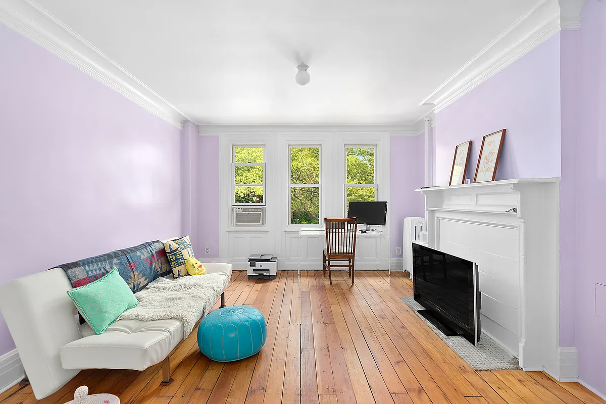 bedroom with a white painted mantel and purple walls set up as an office