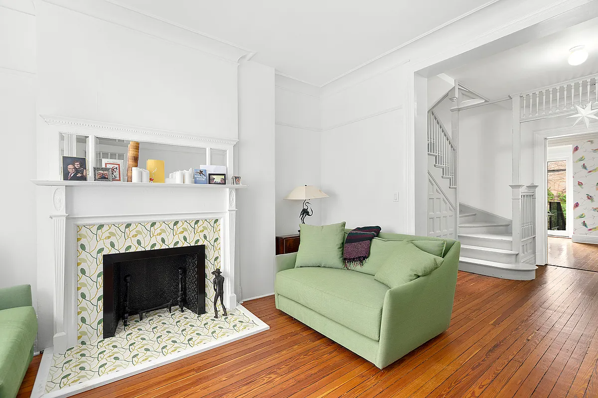 living room with wood floor, white walls, white painted mantel with modern green and yellow tile surround