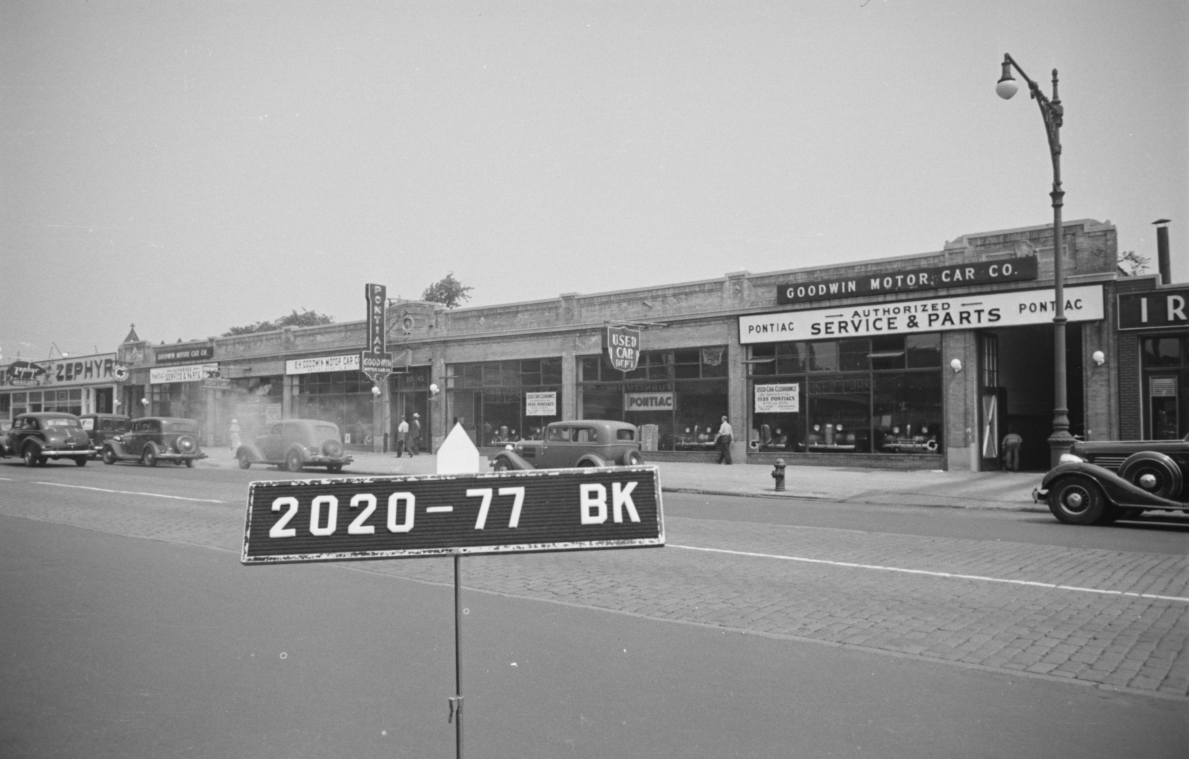 black and white photo of low scale buildings with signs for auto related businesses