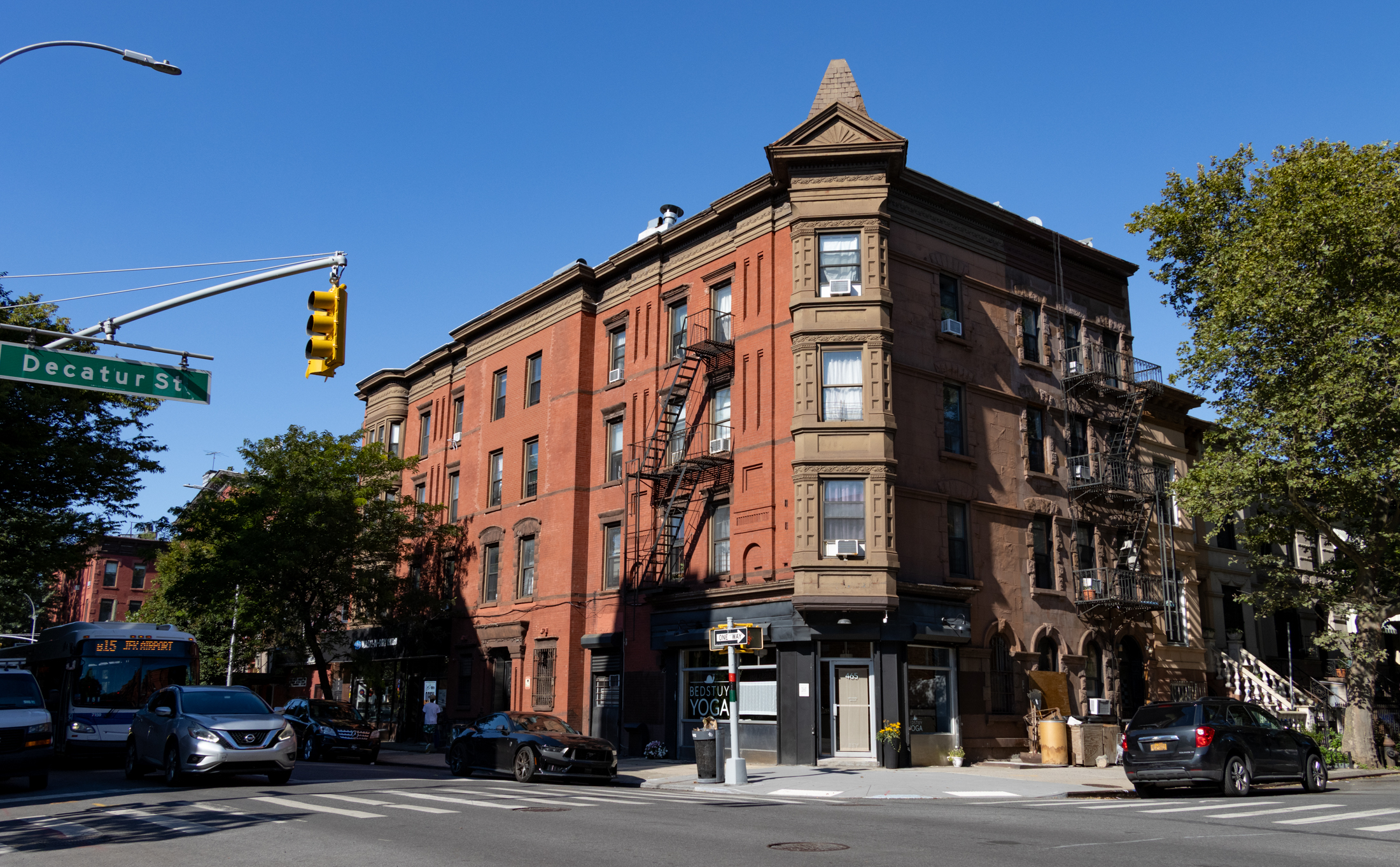 bed stuy corner with a brick building with brownstone details and a corner tower