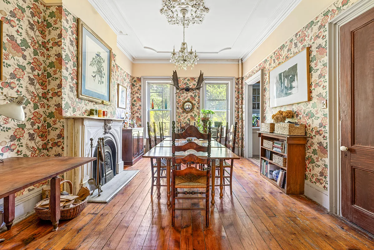 a dining room with wallpaper and a marble mantel