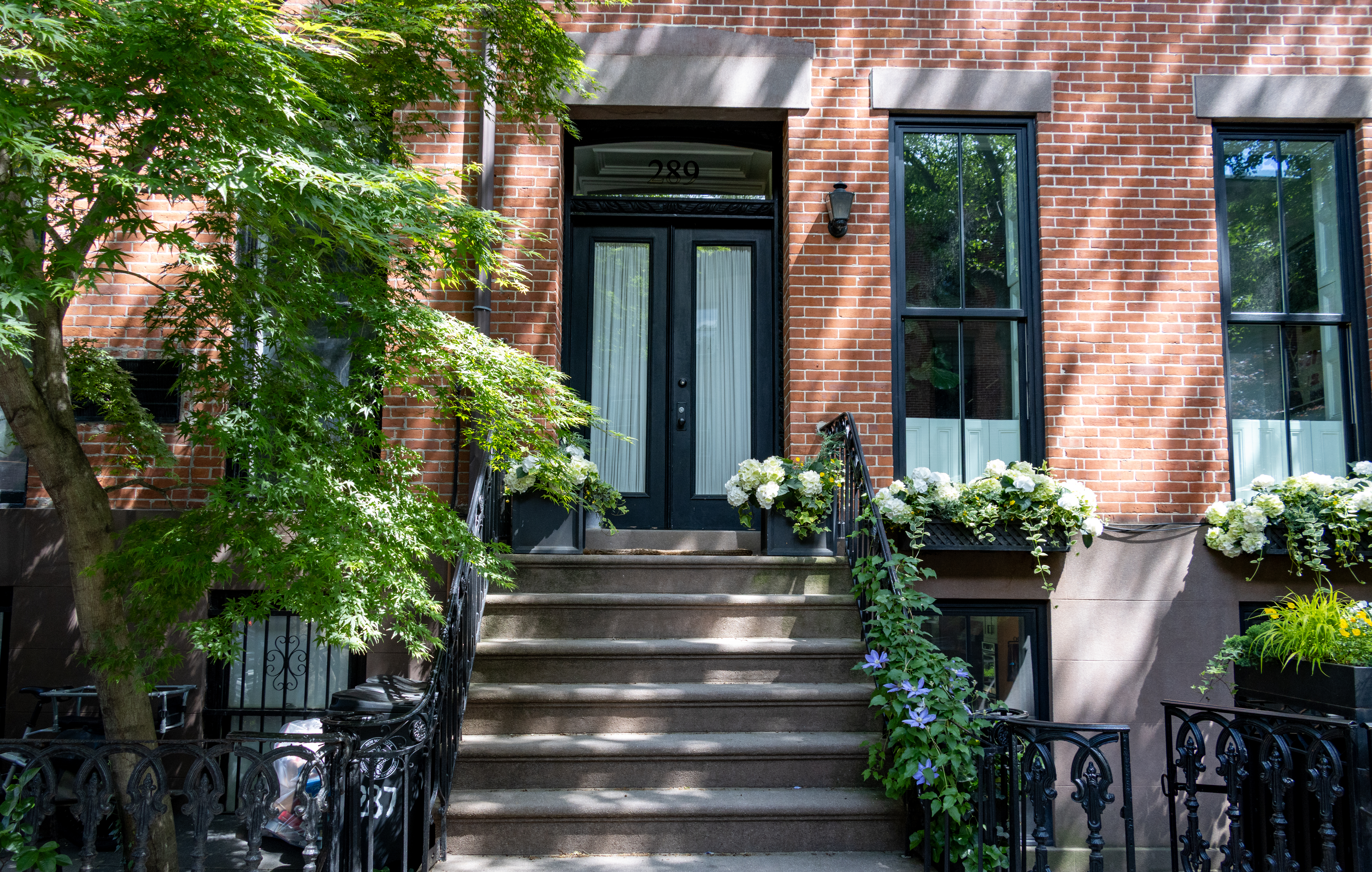 a row house with flowers on the stoop and window boxes