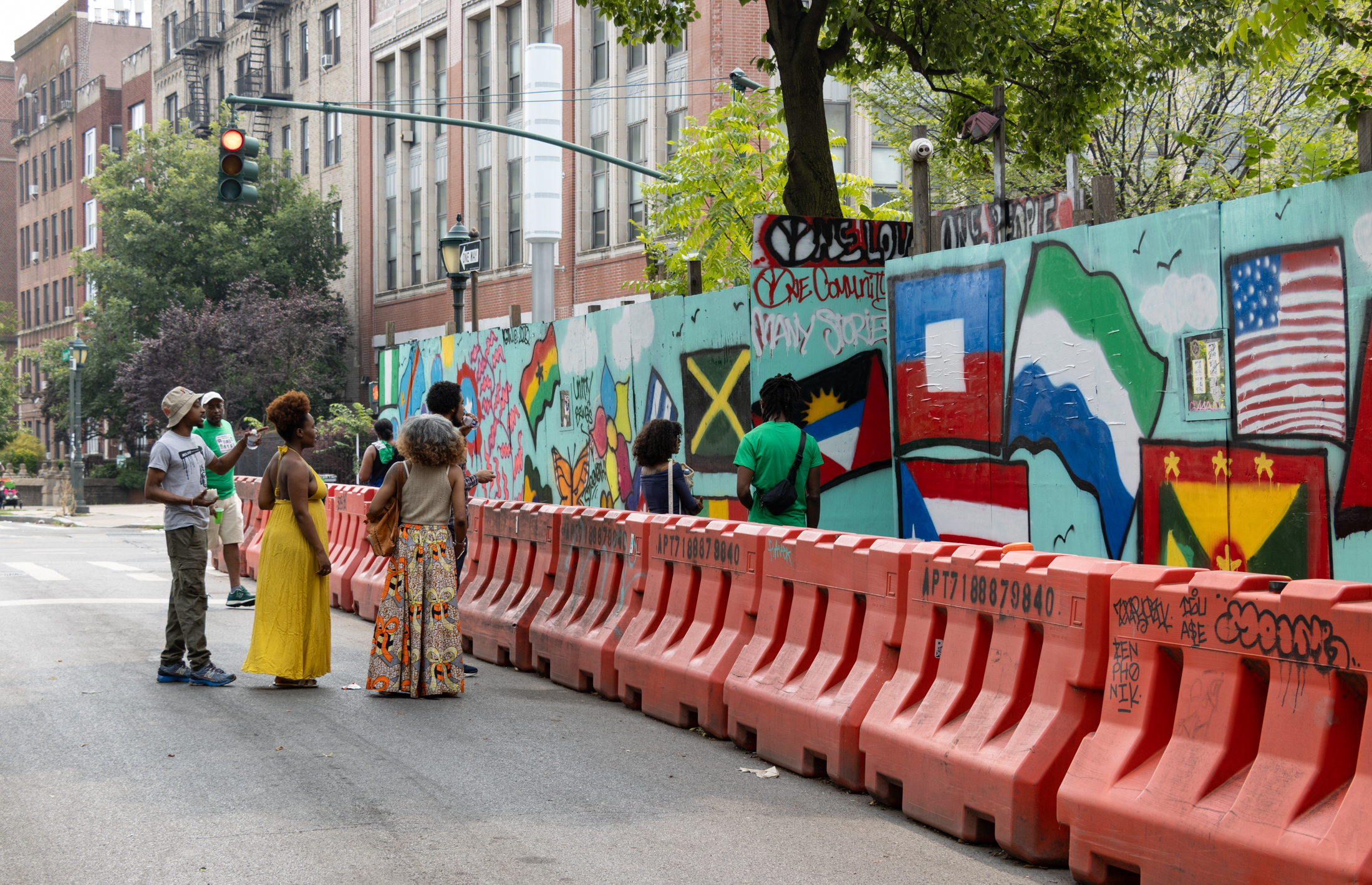 people looking at a mural on a construction fence
