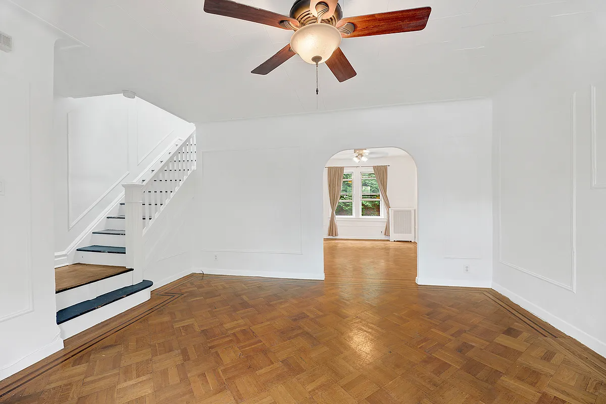 a living room with a wood floor, arched doorway and wall moldings