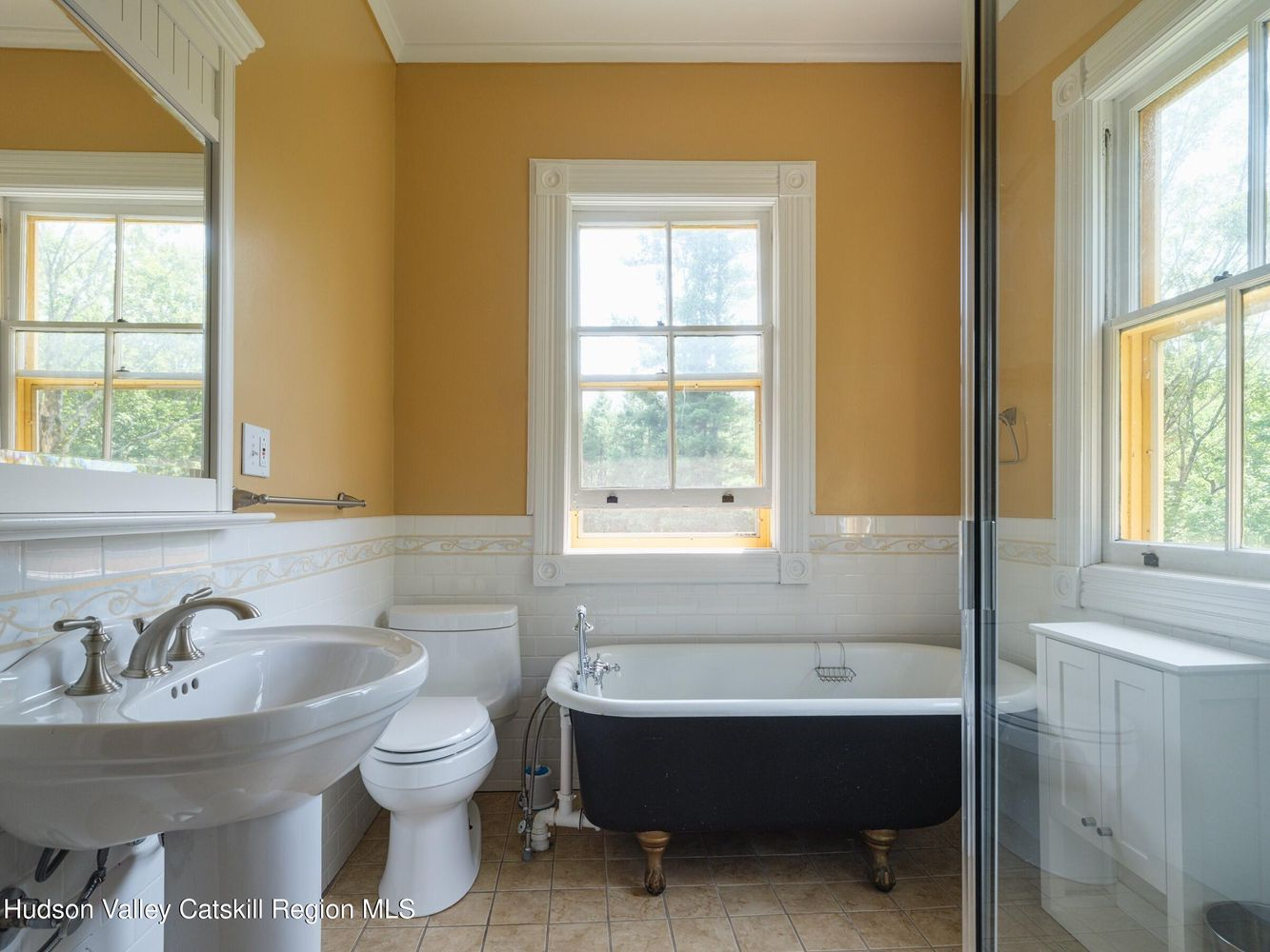 bathroom with claw foot tub, brown tile floor, yellow painted walls