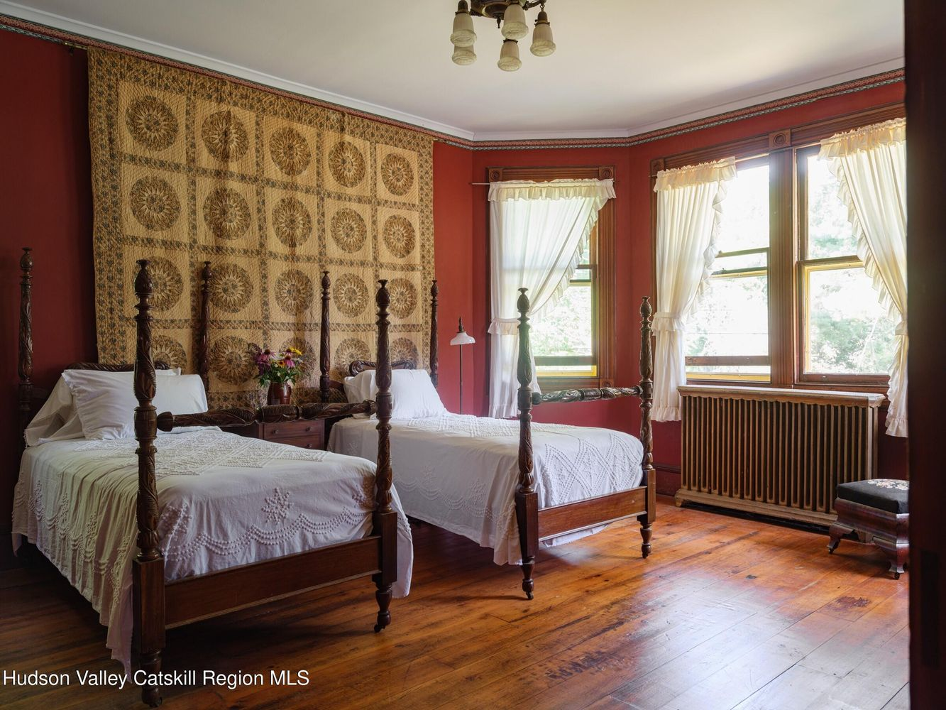 bedroom with red walls, wood floor, two twin beds