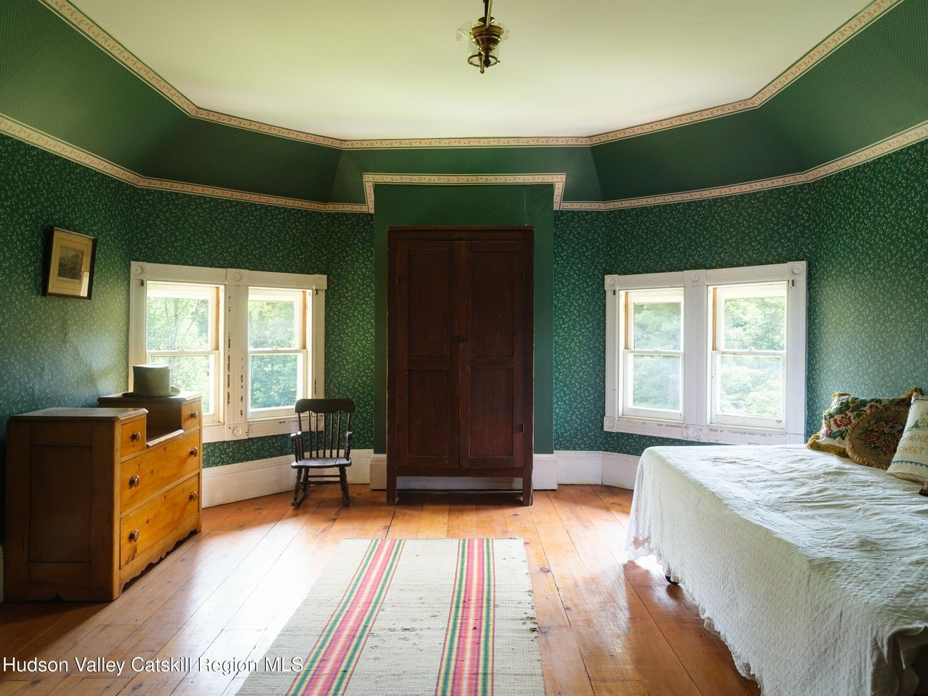bedroom with green wallpaper, wood floor, and two exposures