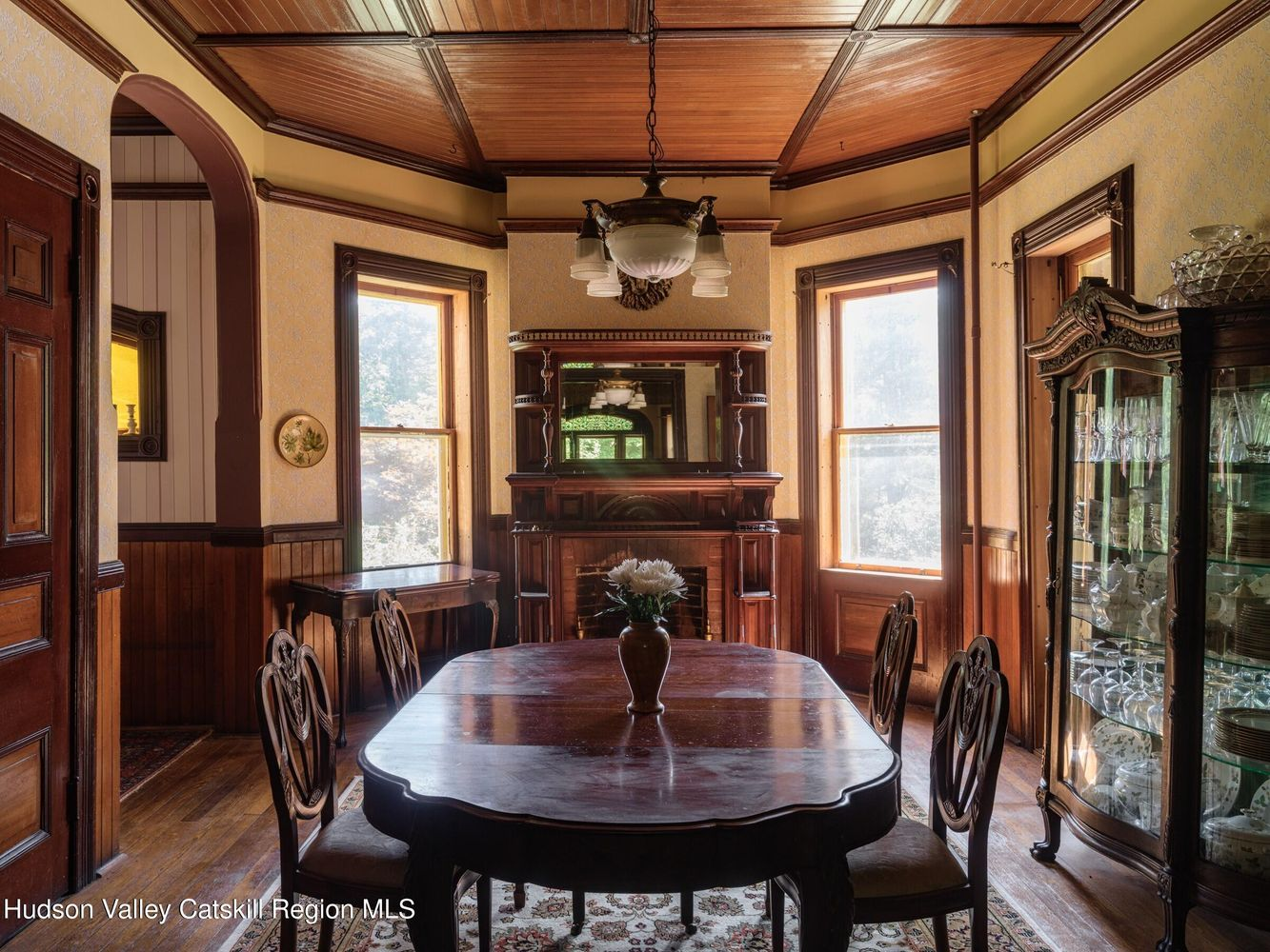 dining room with a wainscoting, wood slat ceiling, mantel, yellow wallpaper