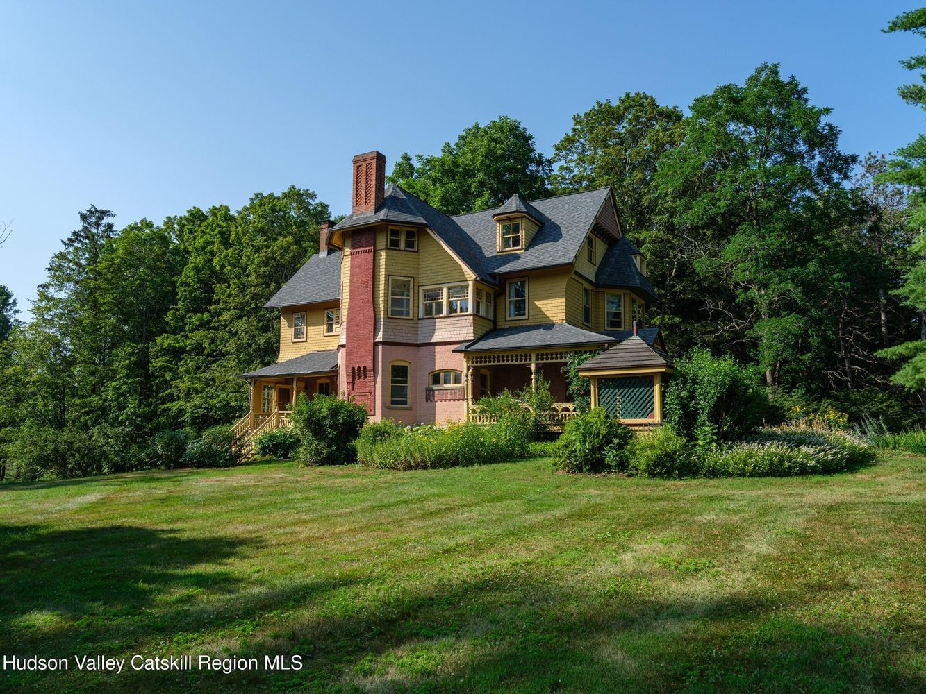 side facade showing chimney, side and front porch, and the wellhouse near the front porch
