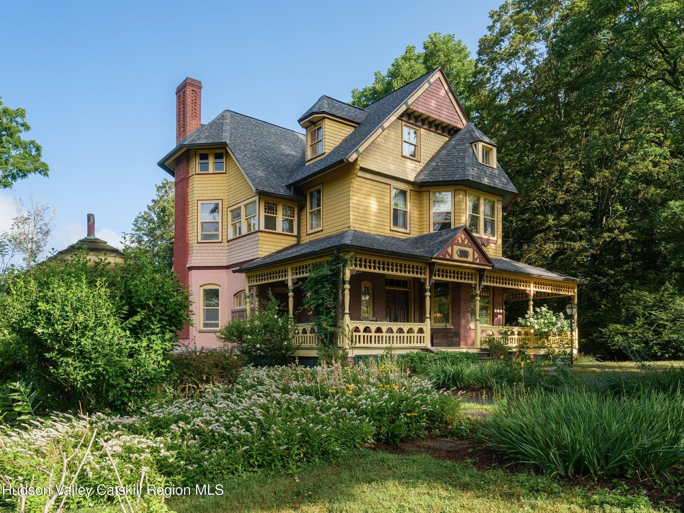 front facade with yellow siding and details in burgundy, mauve, and green