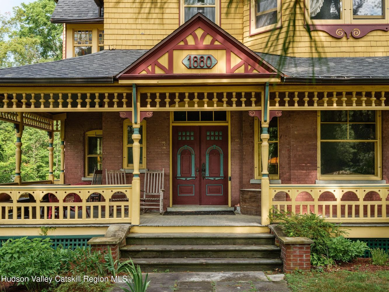porch with "1880" on the pediment and a paint job with yellow, burgandy and green
