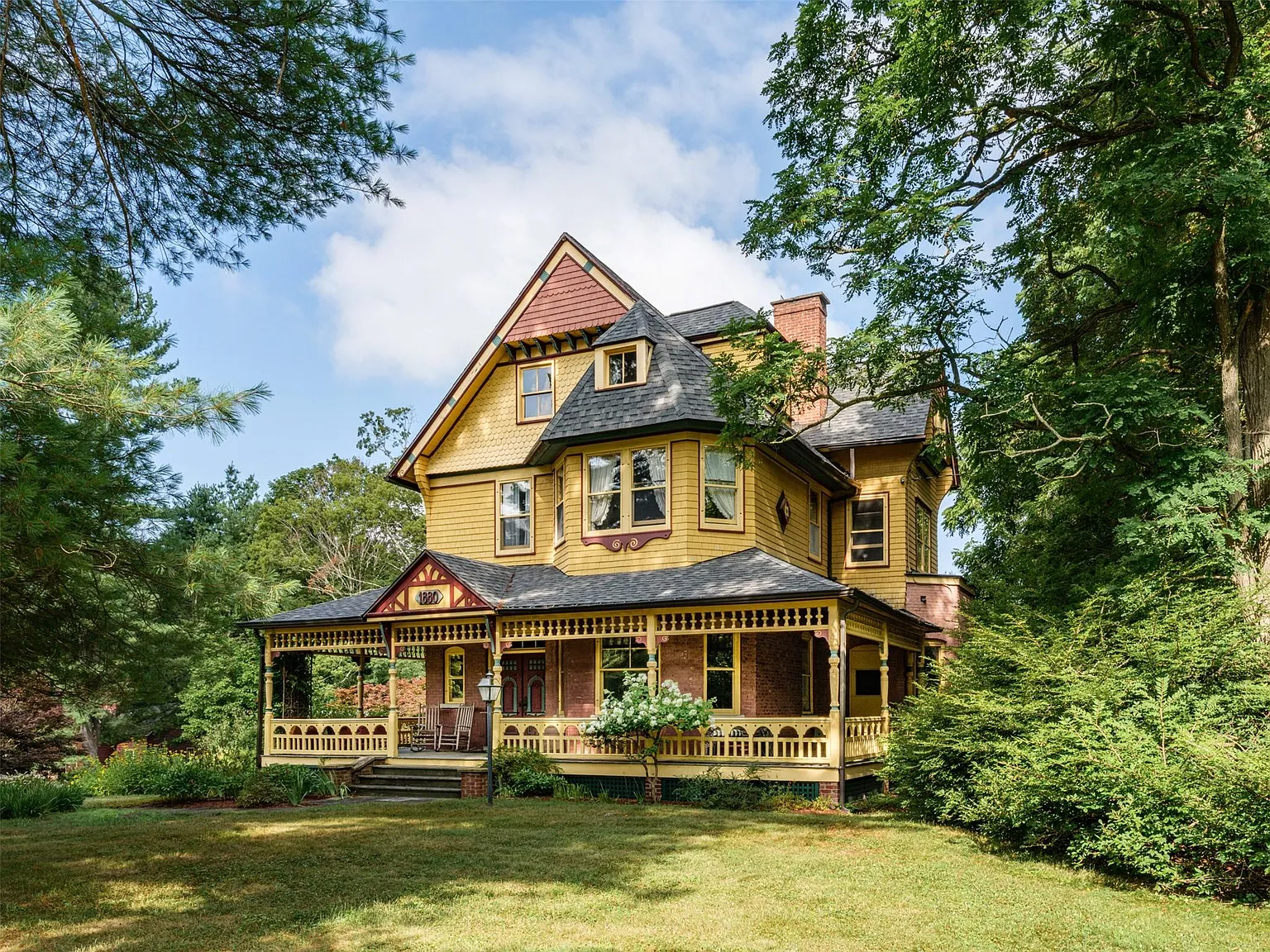 house with yellow siding and shingles and details painted burgundy, green, and other shades