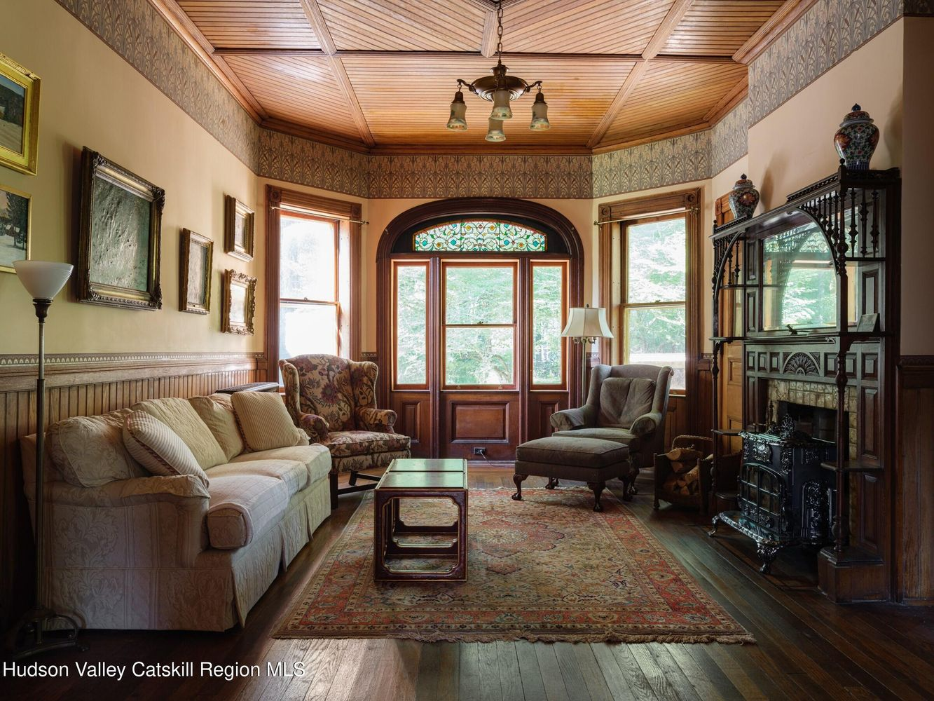 parlor with wood slat ceiling, mantel with fretwork, and wainscoting