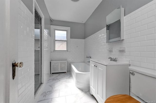 bathroom with white subway wall tile, a tub and a shower