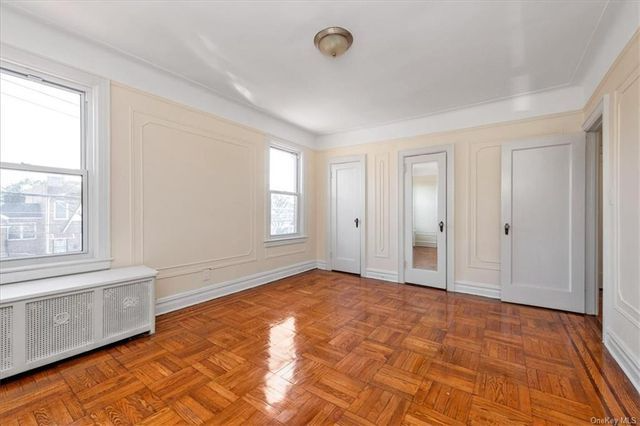 bedroom with two closets, wood floor, wall moldings