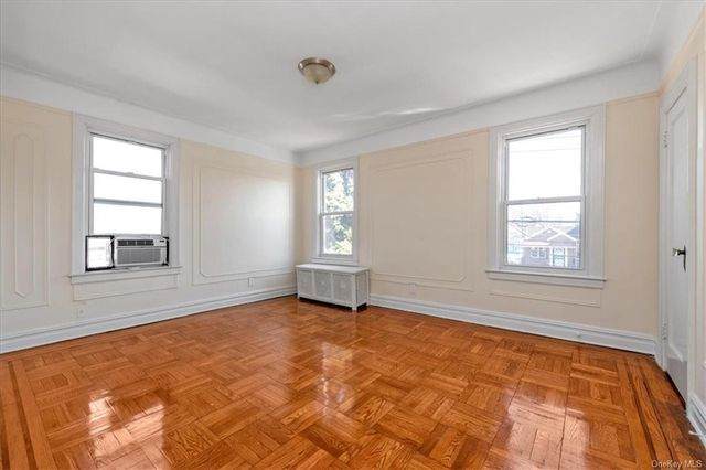 bedroom with two exposures, wood floor, wall moldings