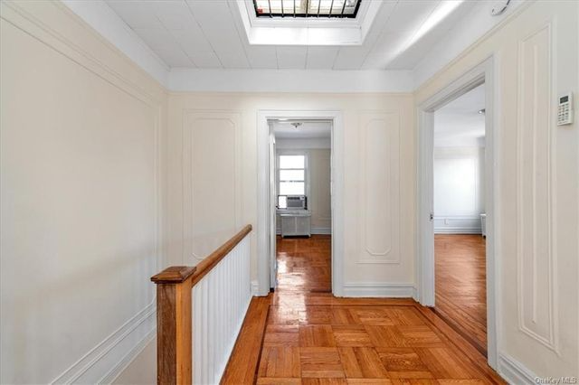 upstairs hall with wood floor, wall moldings, skylight