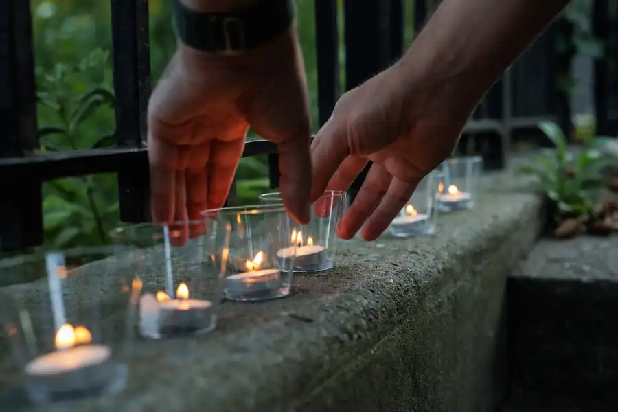 persons hands arranging lit votives at a vigil