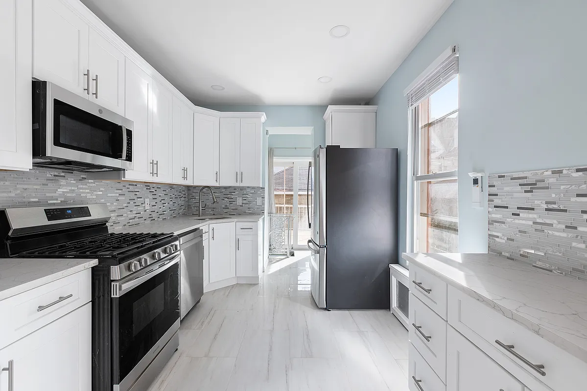 kitchen with gray floor and wall tile, and white cabinets