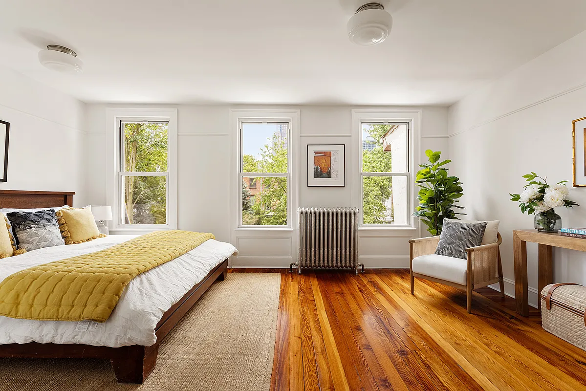 a second floor rear facing bedroom with wood floor, white walls
