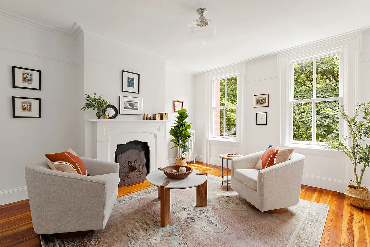 bedroom on the second floor set up as a casual living room with white painted mantel, white walls and a wood floor